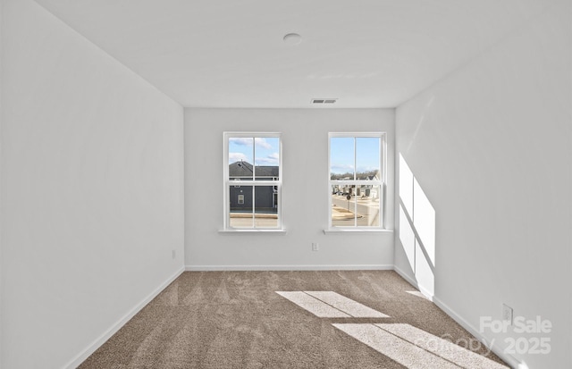 carpeted empty room featuring baseboards