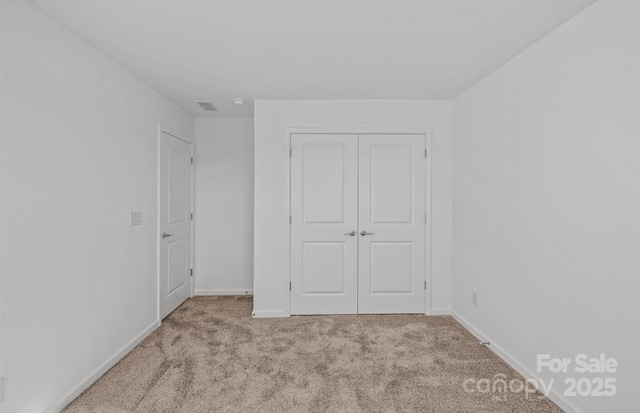 unfurnished bedroom with carpet flooring, baseboards, and a closet