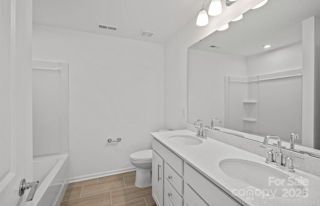 full bathroom with toilet, baseboards, and double vanity