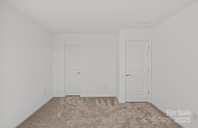 carpeted empty room featuring baseboards