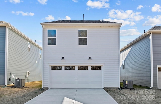 back of property featuring an attached garage, concrete driveway, and central AC unit