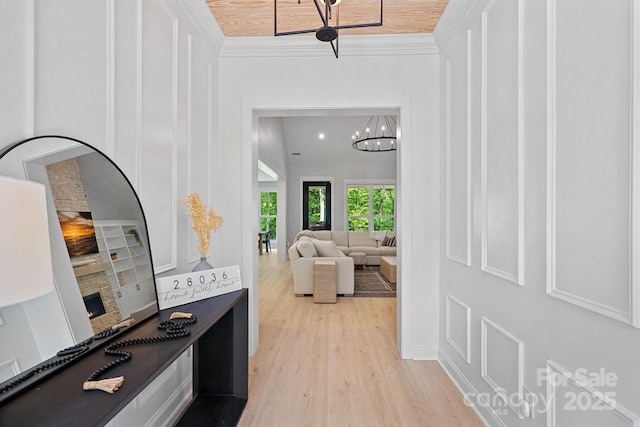 9564 Regent Dr, Davidson, NC 28036 - hallway with crown molding, light wood-style flooring, a chandelier, built in shelves, and baseboards