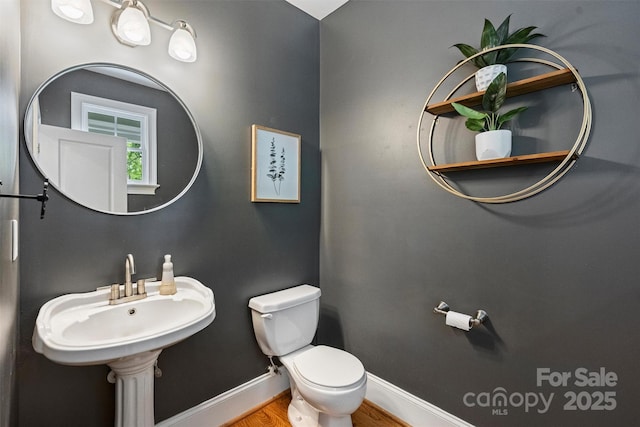 bathroom with toilet, baseboards, and wood finished floors