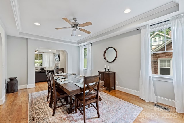 dining space with arched walkways, plenty of natural light, a ceiling fan, a tray ceiling, and recessed lighting