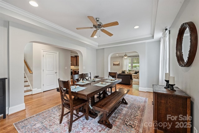 dining space with a ceiling fan, arched walkways, stairs, light wood finished floors, and recessed lighting