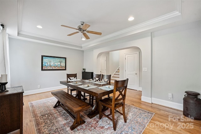 dining area featuring a tray ceiling, arched walkways, a ceiling fan, light wood-type flooring, and recessed lighting