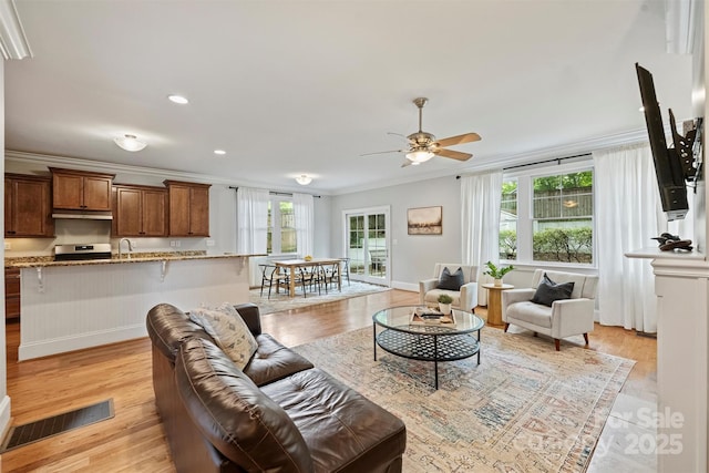 living room with ceiling fan, crown molding, light wood-type flooring, recessed lighting, and baseboards