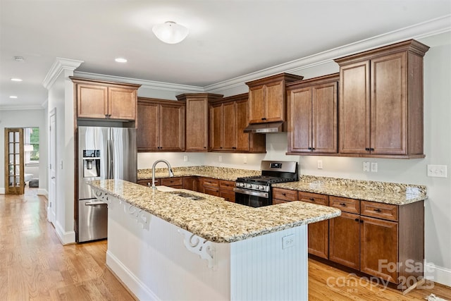 kitchen with appliances with stainless steel finishes, a sink, light wood-type flooring, a kitchen island with sink, and crown molding