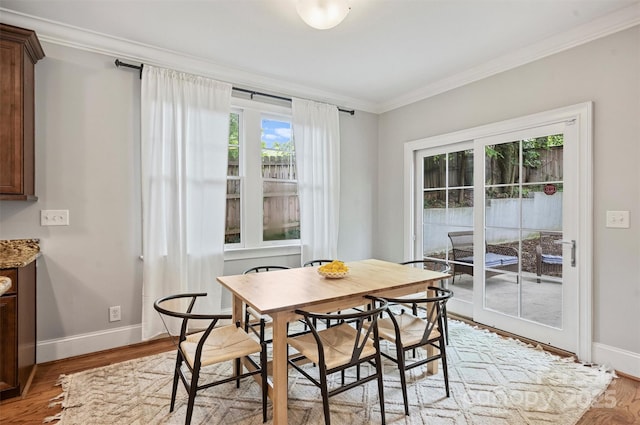 dining space with crown molding, baseboards, and light wood-type flooring