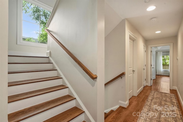 staircase with wood finished floors, recessed lighting, and baseboards