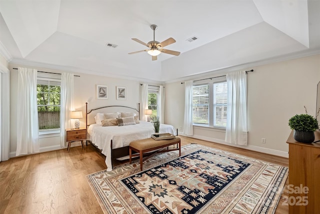bedroom featuring light wood-style flooring, a tray ceiling, a ceiling fan, vaulted ceiling, and crown molding