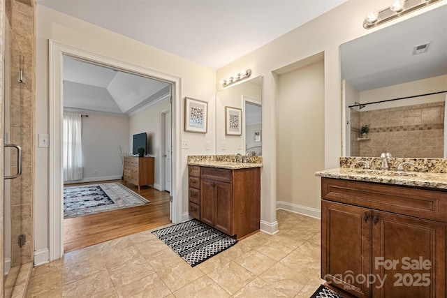 bathroom featuring a stall shower, two vanities, baseboards, and tile patterned flooring