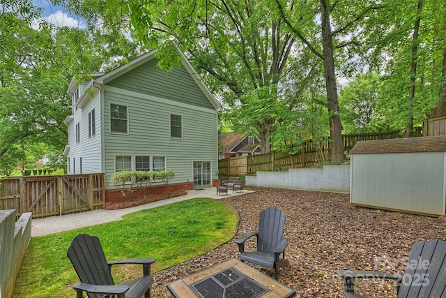 back of property featuring an outdoor fire pit, a patio area, an outbuilding, a storage unit, and a gate