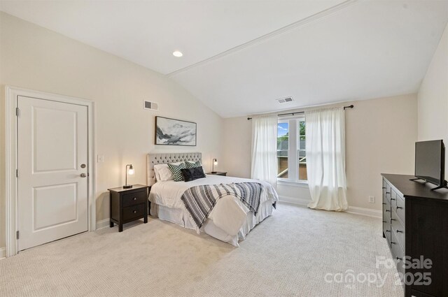 bedroom with vaulted ceiling, light colored carpet, and baseboards