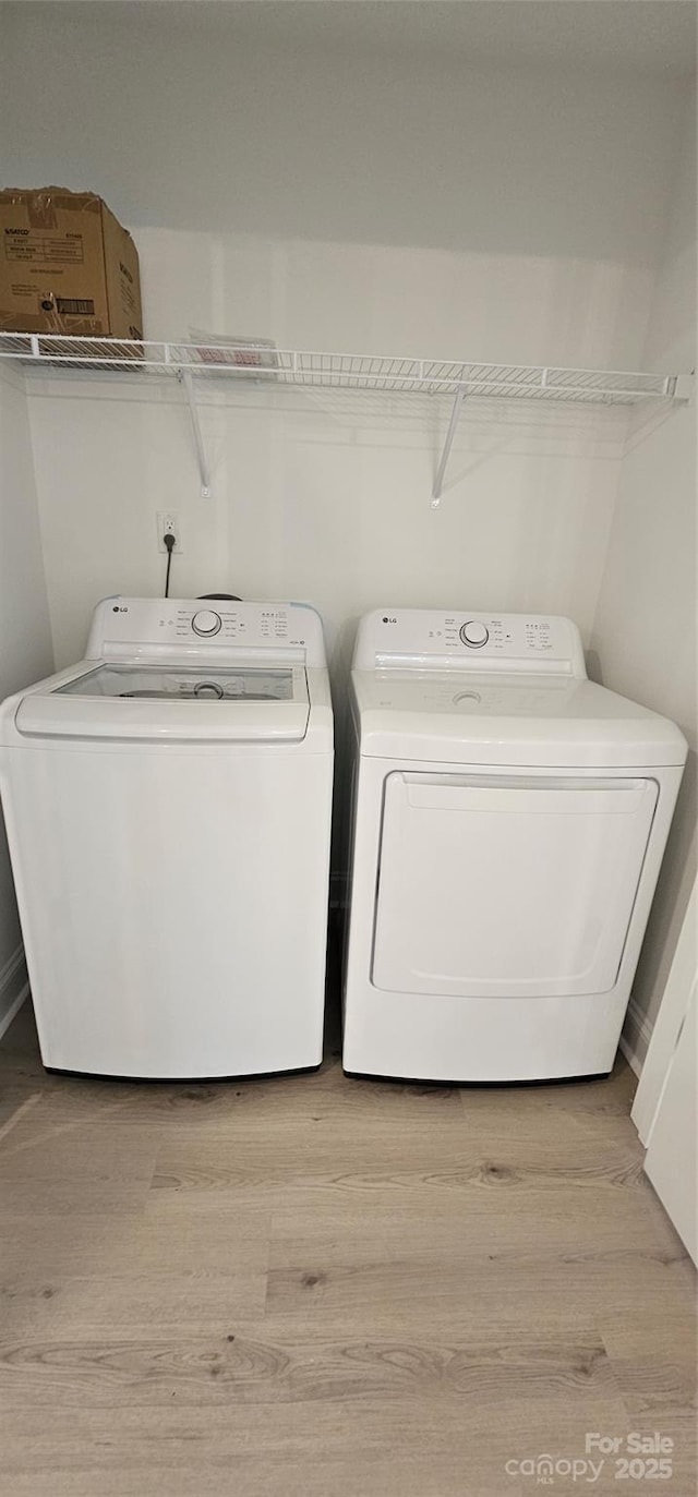 clothes washing area featuring washer and dryer and light wood-style floors