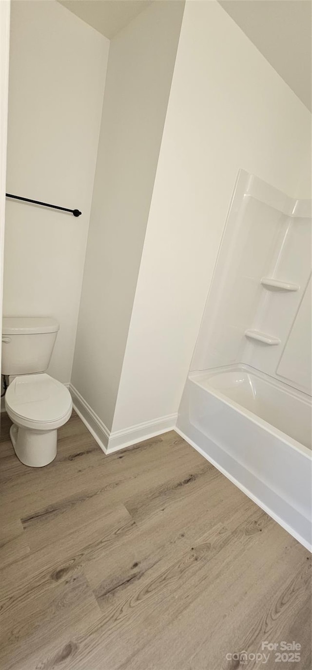 full bath featuring wood finished floors, toilet, baseboards, and shower / bath combination