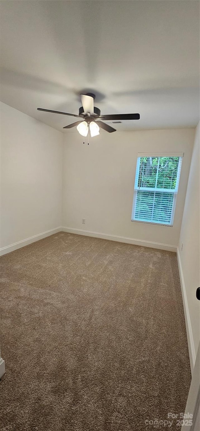 carpeted spare room with a ceiling fan and baseboards