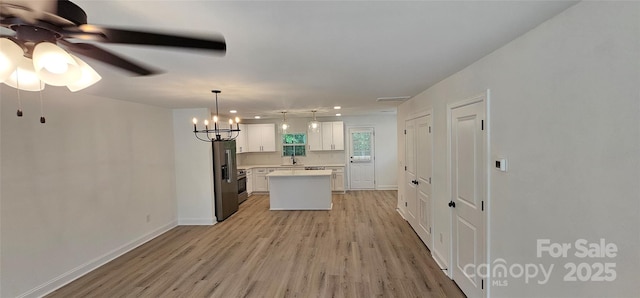 kitchen featuring a sink, light wood finished floors, white cabinetry, a center island, and light countertops