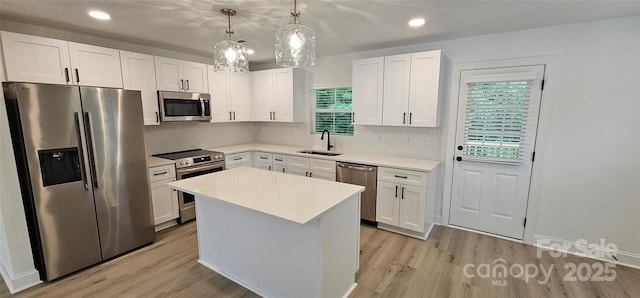 kitchen featuring appliances with stainless steel finishes, light wood-style floors, a center island, tasteful backsplash, and recessed lighting