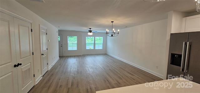 unfurnished dining area featuring baseboards, a chandelier, and wood finished floors