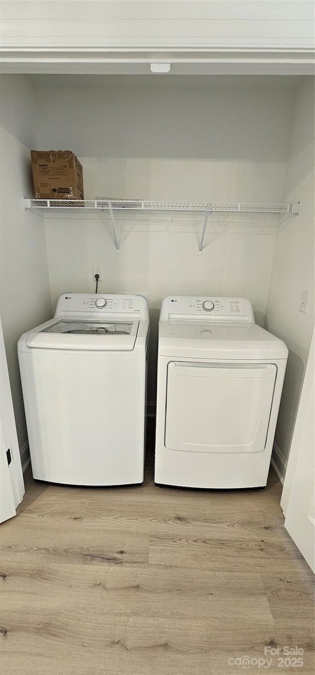 clothes washing area featuring independent washer and dryer and light wood-style flooring