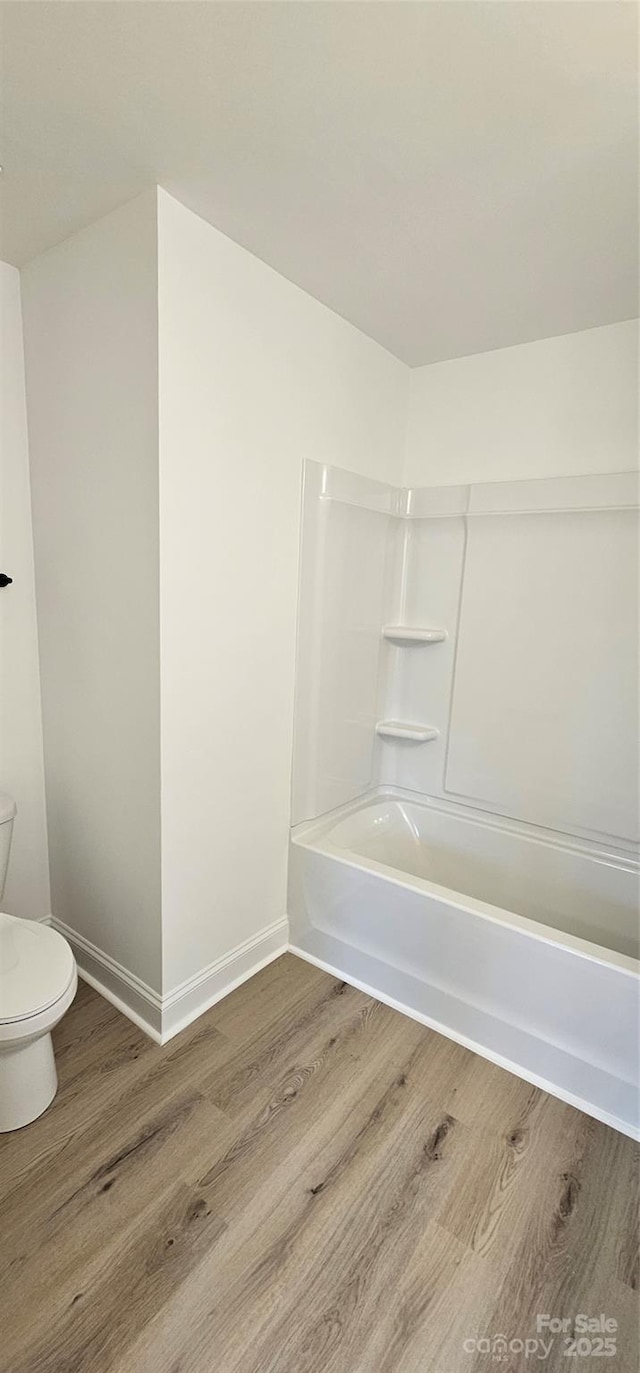 bathroom featuring wood finished floors, toilet, baseboards, and shower / tub combination