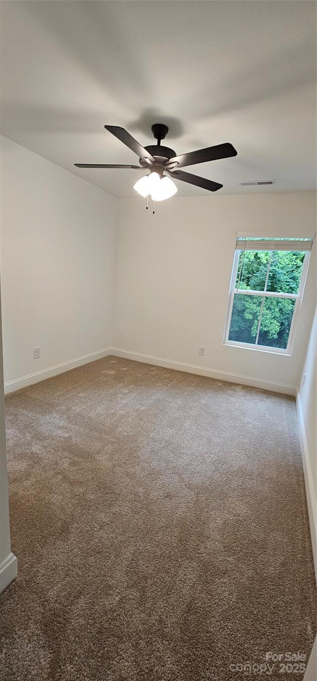 carpeted spare room with a ceiling fan and baseboards