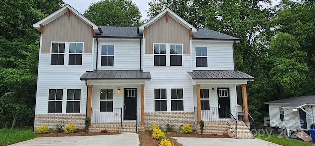 view of front of house featuring covered porch, a standing seam roof, board and batten siding, metal roof, and a shingled roof