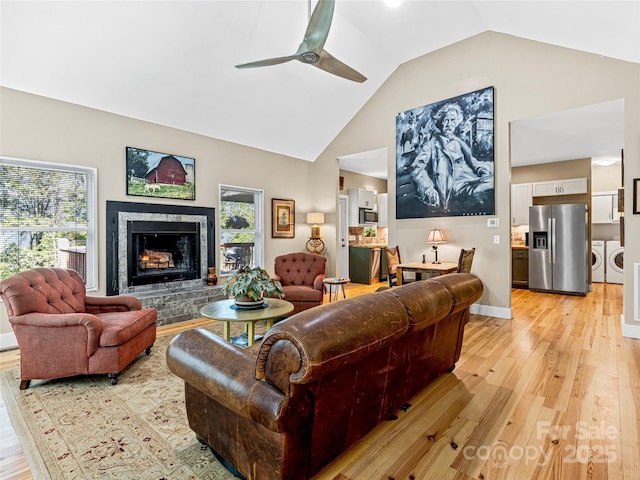 1846 Utah Mountain Rd, Waynesville, NC 28785 - living area featuring washing machine and dryer, light wood-style flooring, a ceiling fan, a fireplace with raised hearth, and high vaulted ceiling