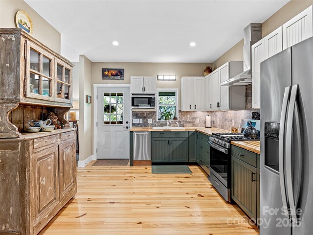 1846 Utah Mountain Rd, Waynesville, NC 28785 - kitchen with stainless steel appliances, wall chimney exhaust hood, light wood-type flooring, tasteful backsplash, and recessed lighting