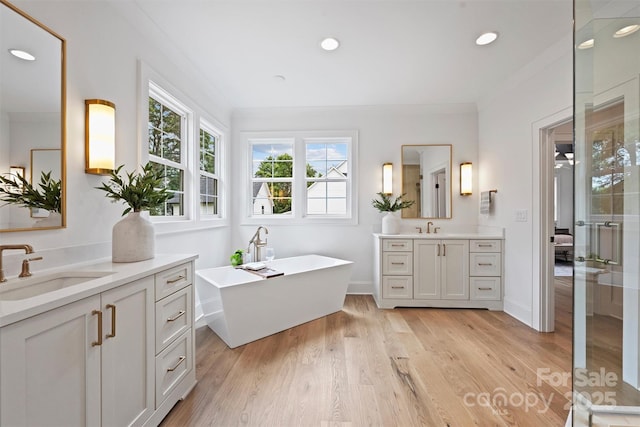 922 Everett Pl, Charlotte, NC 28205 - bathroom featuring two vanities, wood finished floors, a freestanding bath, recessed lighting, and baseboards
