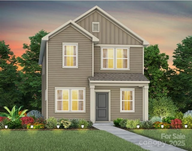 traditional home with board and batten siding, a front yard, and roof with shingles