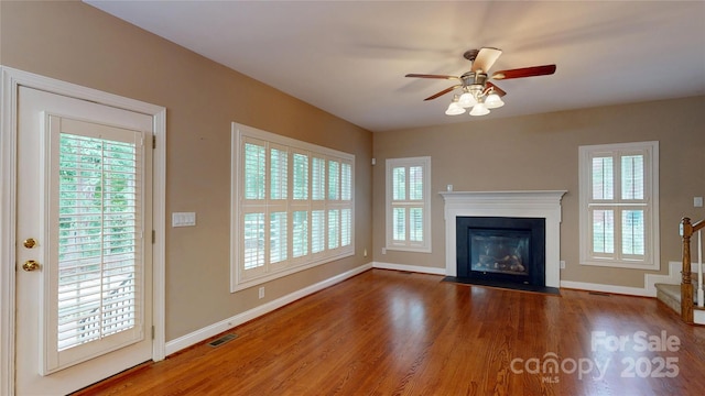 unfurnished living room featuring baseboards, wood finished floors, and a ceiling fan