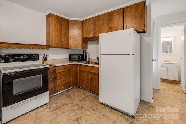 kitchen featuring freestanding refrigerator, range with electric stovetop, black microwave, brown cabinetry, and a sink