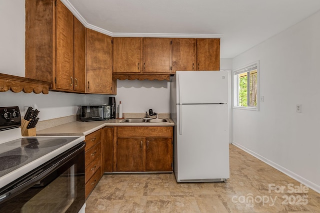 kitchen with freestanding refrigerator, black / electric stove, a sink, brown cabinets, and light countertops