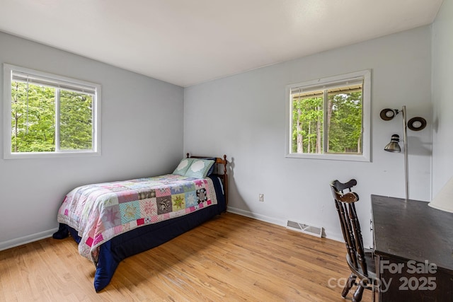 bedroom featuring multiple windows, baseboards, and wood finished floors
