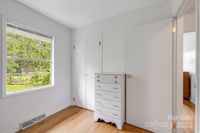 bedroom with light wood-type flooring, a closet, and baseboards