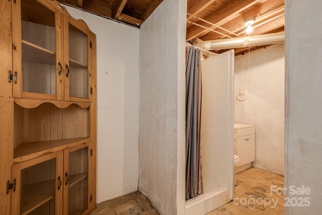 full bathroom featuring a stall shower, toilet, and concrete block wall