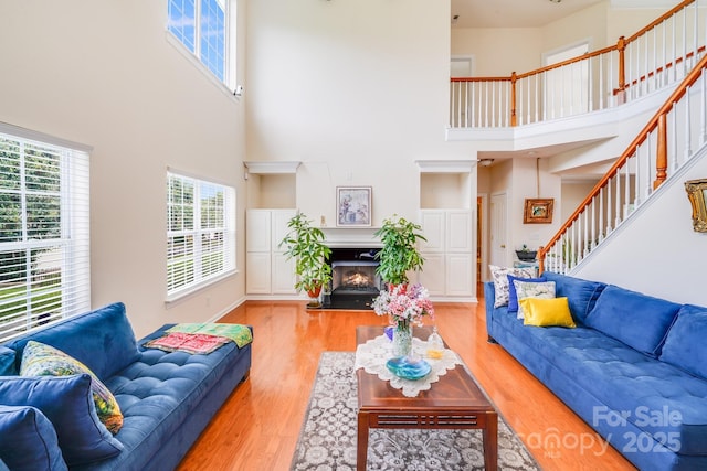 6227 Castlecove Rd, Charlotte, NC 28278 - living room with a high ceiling, light wood finished floors, stairs, and a lit fireplace