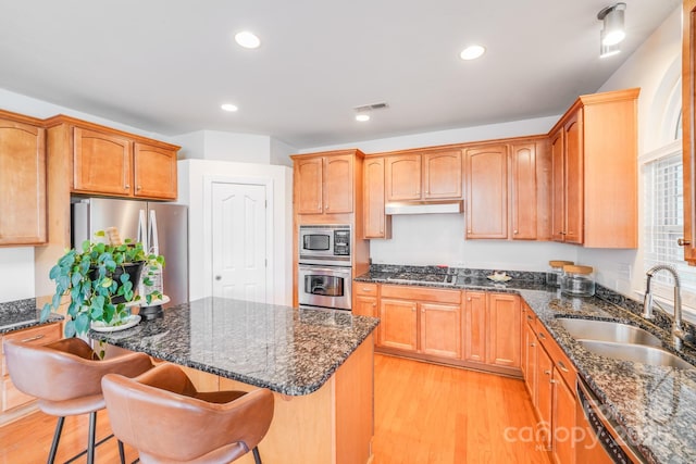 6227 Castlecove Rd, Charlotte, NC 28278 - kitchen featuring stainless steel appliances, light wood-style flooring, a kitchen island, a breakfast bar area, and dark stone counters