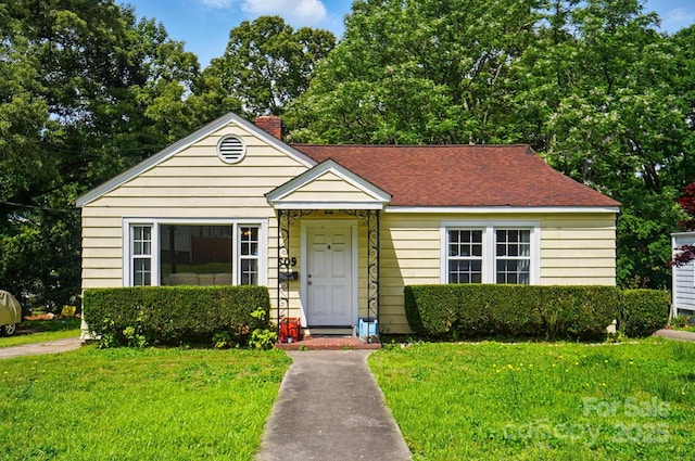 bungalow-style house with a front yard, a chimney, and a shingled roof