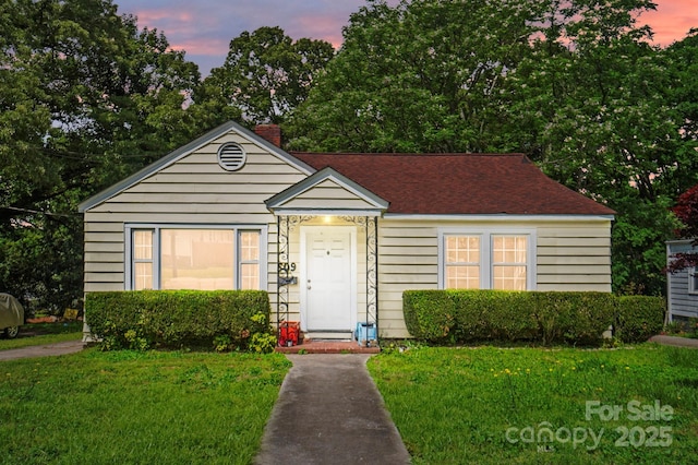 bungalow-style house with a front yard, a chimney, and roof with shingles