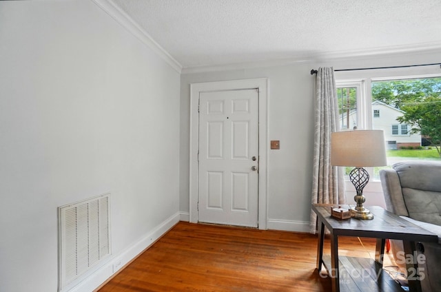 entryway featuring ornamental molding, wood finished floors, baseboards, and a textured ceiling