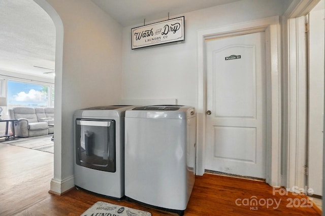 clothes washing area featuring independent washer and dryer, arched walkways, and dark wood-style floors