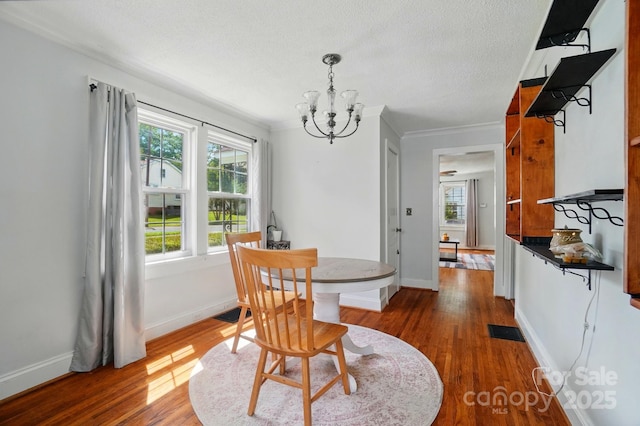 dining area featuring a chandelier, healthy amount of natural light, dark wood-type flooring, ornamental molding, and baseboards