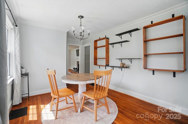 dining room featuring a chandelier, ornamental molding, wood finished floors, and baseboards