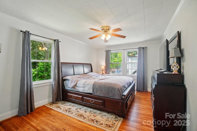 bedroom with light wood-style floors, baseboards, ornamental molding, and a ceiling fan