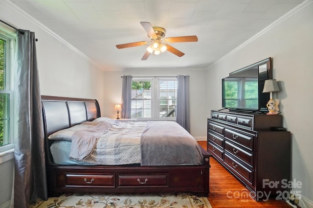 bedroom with multiple windows, wood finished floors, crown molding, and ceiling fan