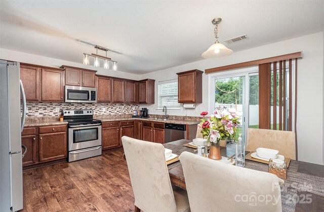 kitchen with stainless steel appliances, dark wood-style flooring, decorative light fixtures, and a sink