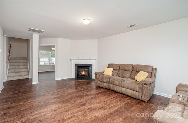living area with baseboards, stairway, dark wood finished floors, and a fireplace with flush hearth